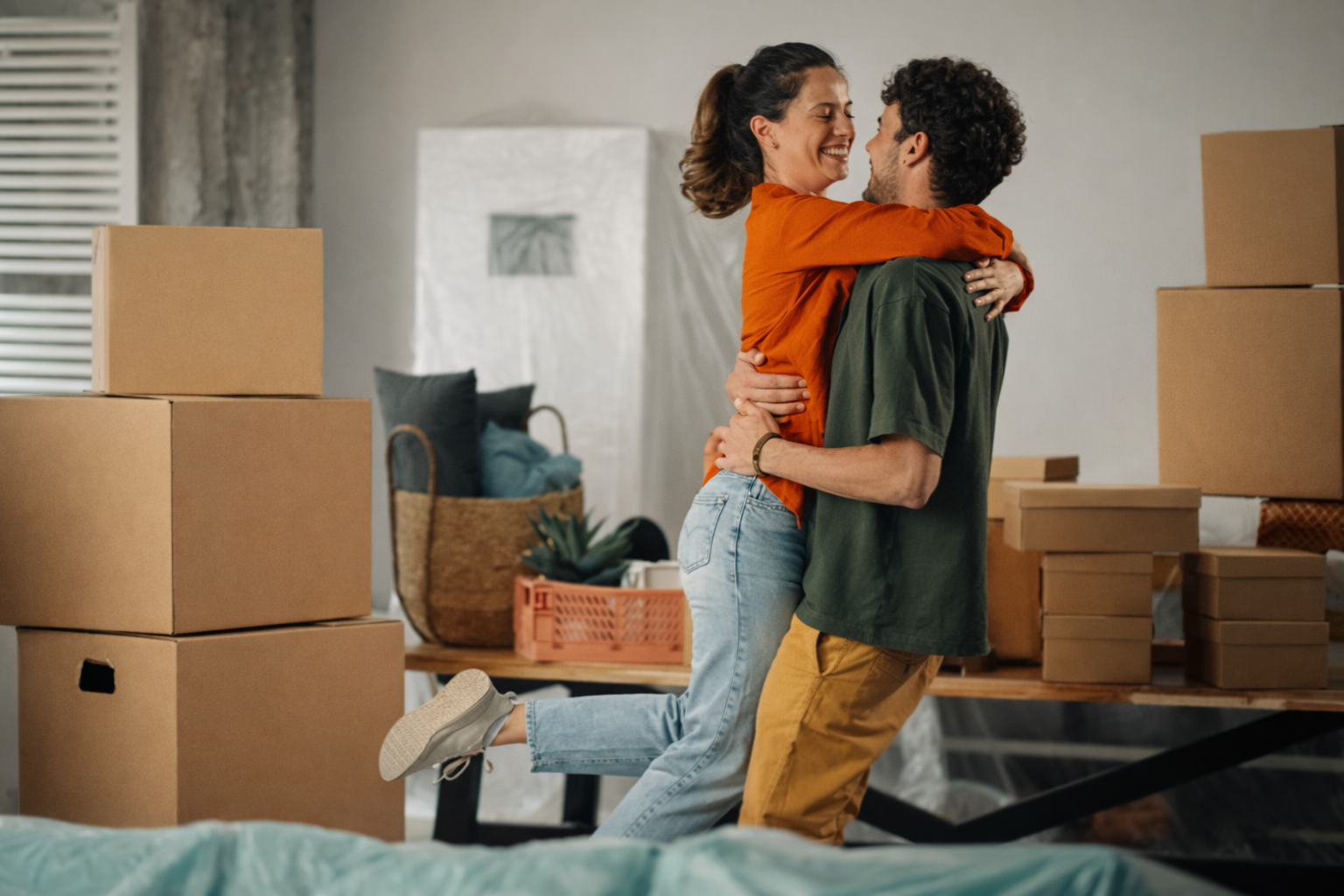 Happy couple embracing in their new home surrounded by moving boxes